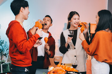 Group of young Asian man and women as friends having fun at a New Year's celebration, holding gift boxes standing by Christmas tree decoration, midnight countdown Party at home with holiday season.