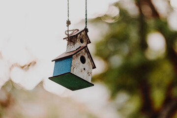 A rustic, wooden birdhouse hangs delicately by a string
