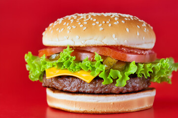 A hamburger with red and green food on a . Burger meal beef concept. Close up of a hamburger and big fast food lying on red. Close up of a hamburger and big fast food lying lifestyle on the.