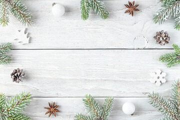 Christmas composition. Frame made of snowy fir branches, decorations, pine cones on white wooden background. Flat lay. Happy New Year and winter holidays background. Top view