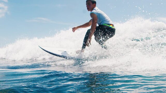 Teen boy surfer rides the wave and makes sharp turn with spray. Tropical surfing in the Maldives