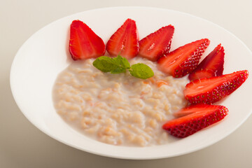 White with a strawberry and porridge. food organic healthy concept. a plate of oatmeal with strawberries and whites for breakfast. a plate of oatmeal with strawberries and white white slices on a.