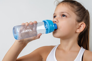 Girl in gray with bottle on the . female w person concept. girl drinking water from bottle on a gray . a girl in gray drinks water from a bottle on a lifestyle white.