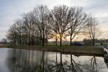 Bare trees and sunset reflections by a canal