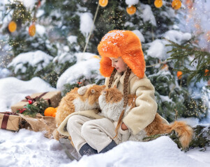 A little cheerful girl kid with New Year's fruit orange and with a pet cat at winter