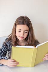 Sad girl reading a book at home. Girl student teaches lessons to school.