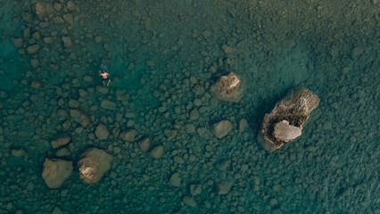 Aerial view blue sea at sunset in summer. Tropical landscape with man, clear water, stones, sandy beach.
