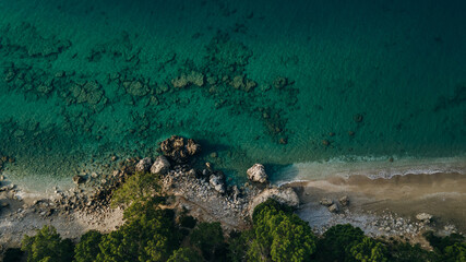 Aerial view blue sea at sunset in summer. Tropical landscape with man, clear water, stones, sandy beach.