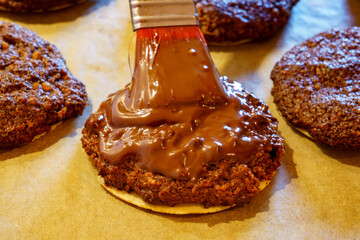 Making Christmas cookies at home. Nuremberg Elisen gingerbread is covered with liquid chocolate after baking. Close-up