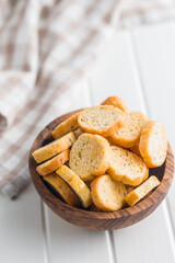 Sliced roasted bruschetta bread in bowl on white table.