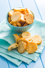 Sliced roasted bruschetta bread in bowl on blue table.