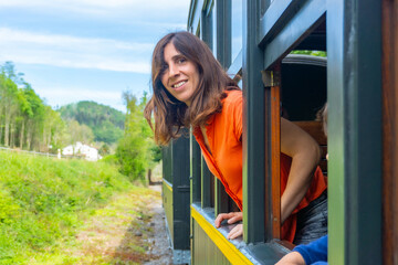 A woman is sitting in a train car with her head out the window