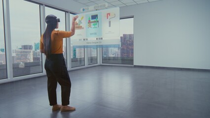 Fototapeta premium Talented Asian female designer in augmented reality headset uses virtual interior design software to arrange stylish apartment or office room with 3D furniture and equipment. Futuristic VFX animation.
