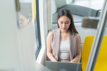 Asian Woman Using Laptop While Commuting in A Skytrain 