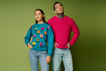 A stylish duo poses in vibrant sweaters against a green backdrop, radiating confidence and charm.