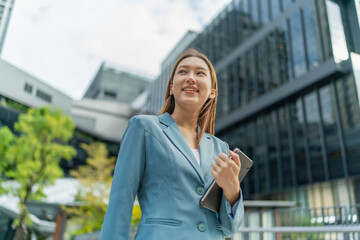 Fototapeta premium Young Businesswoman Using Digital Tablet In Front A Modern Office Building in a Financial District