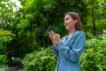 Young Businesswoman In Blue Suit Using Phone Amid Greenery of A Park In The City