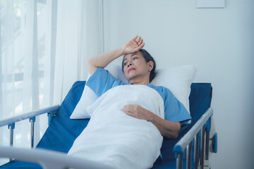 Patient's pensive moment: A thoughtful elderly woman rests in a hospital bed, gazing pensively out the window.  A poignant image conveying contemplation, recovery.