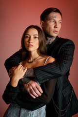 Attractive couple embraces closely, highlighting their fashion choices and striking features.