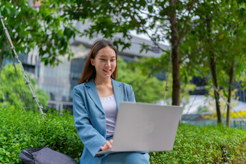 Asian Woman Sitting In A Garden and Using Laptop