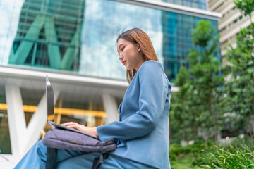 Young Businesswoman Using Laptop In Front A Modern Office Building