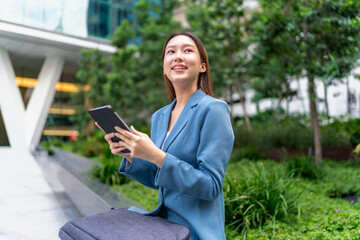 Young Asian Businesswoman Using Digital Tablet Outdoor In Front Modern Office Building