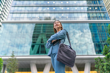 Fototapeta premium Portrait of a young and confident businesswoman standing in front a modern office building in the financial district