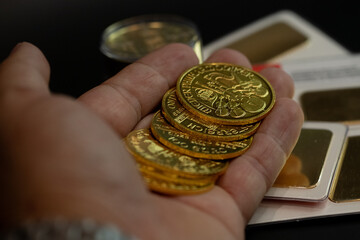 cluse-up hand counting gold coins on a back table with more gold. business, investments, finance and savings. Stock photo