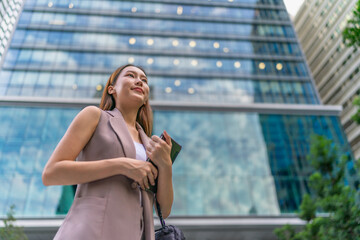 Fototapeta premium Asian Businesswoman Using Tablet In Front of A Modern Office Building In the Financial District