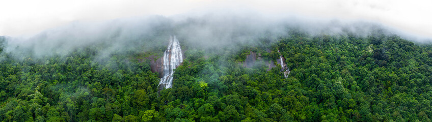 Aerial view of beautiful waterfall village in the lush green rain cloud and foggy cover tropical...