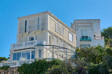 Obraz premium Showcases a stunning Mediterranean-style villa in Marseille, featuring classic architecture with balconies and lush vegetation, perfect for representing luxury and elegance on the French coast.