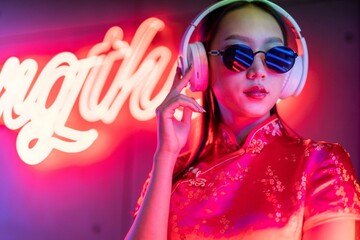 Futuristic Asian Woman in Red Cheongsam with Sunglasses and Headphones in a Neon-Lit Studio