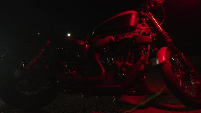 Motorcycle cruiser with headlights on in night parking lot. Slow motion. Front view. Riding motorcycle requires extreme concentration, prudence and quick reaction