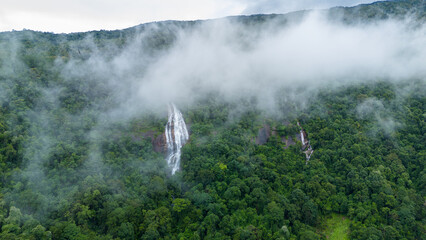Aerial view of beautiful waterfall village in the lush green rain cloud and foggy cover tropical...