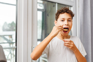 Delicious snack, fast food, junk food. A little happy and cheerful boy is eating French fries while...