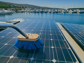 Photography of solar panels on a boat docked at the port being cleaned up with a blue brush and...