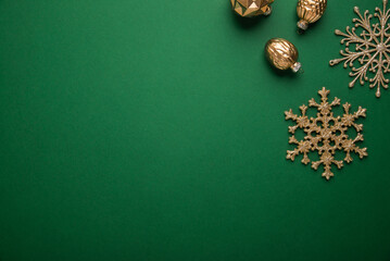 Merry Christmas and Happy Holidays greeting card, frame, banner. New Year. Noel. Golden Christmas ornaments on green background top view. Winter xmas holiday theme. Flat lay
