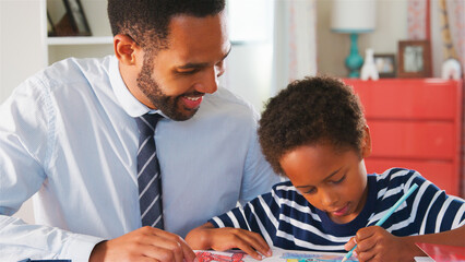 Fototapeta premium Father With Son Sitting At Desk In Bedroom At Home Colouring In Picture