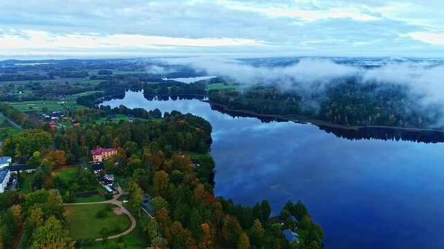 Lake, woodland and low flying clouds, aerial drone view