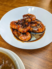 Top view of a round white plate of assam prawn