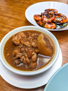 Top view of a round white plate of nyonya dish ayam pongteh and assam prawn