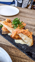 Smoked salmon rilettes made using sourdough bread served on a black charcuterie board 