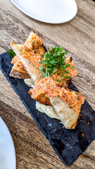 Smoked salmon rilettes made using sourdough bread served on a black charcuterie board