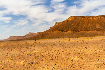 Dry stone desert and lonely table mountain in the background. Morocco

