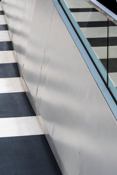 An intriguing diagonal view of a modern staircase with sleek metal and glass elements, creating an abstract pattern of light and shadow, enhancing its visual depth.