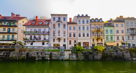 photography of colourfull buildings in front of the river Ljubljanica in Ljubljana, Slovenia at day during a foggy morning