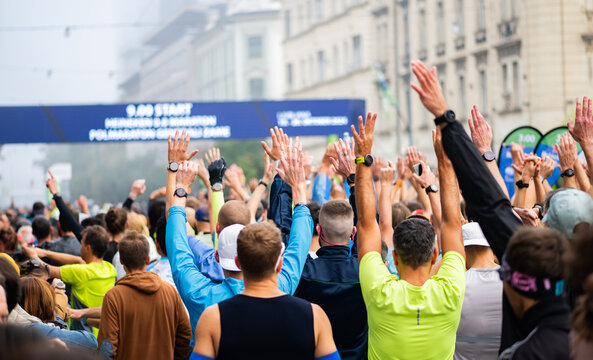 photography from the back of many Runners with smart watches and hands in the air ready to start the marathon. non recognizable persons