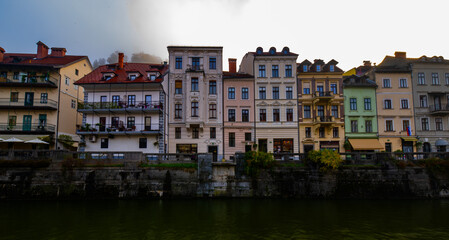 photography of colourfull buildings in front of the river Ljubljanica in Ljubljana, Slovenia during a foggy morning