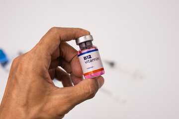 doctor's hand holds a bottle b12 vitamin injection. health and medical concepts
