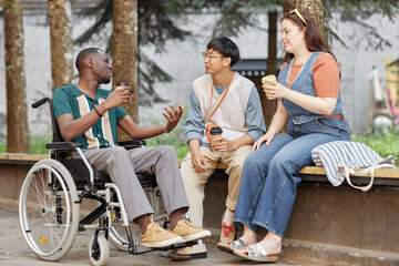 Full length portrait of smiling African American man with disability chatting with friends in city setting outdoors enjoying day together